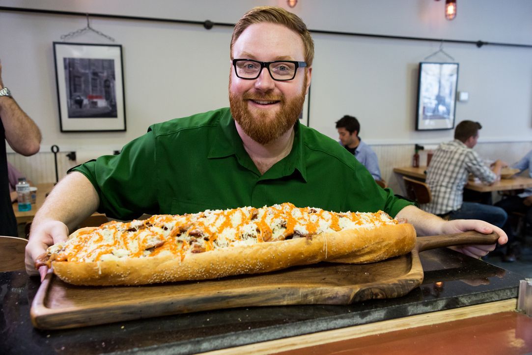 Josh Denny ist gespannt, was das riesige Sandwich aus dem "Jake's Sandwich Board" zu bieten hat. Doch damit ist seine Reise durch Philadelphia noch... - Bildquelle: Ben Leuner 2016, Television Food Network, G.P. All Rights Reserved.
