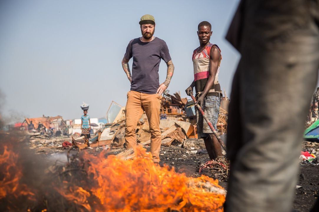 Reporter Oliver Plöger (l.) blickt hinter die Kulissen der Elektroschrottdeponie von Agbogbloshie in Ghana, auf und vor der knapp 50.000 Menschen le... - Bildquelle: ProSieben MAXX