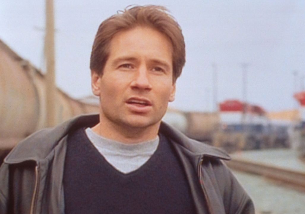 Mulder (David Duchovny) beobachtet auf einem Bahnhof, dass mehrere Japaner ein Wesen, dass einem Außerirdischen ähnelt, in einen regierungseigenen E... - Bildquelle: TM +   2000 Twentieth Century Fox Film Corporation. All Rights Reserved.