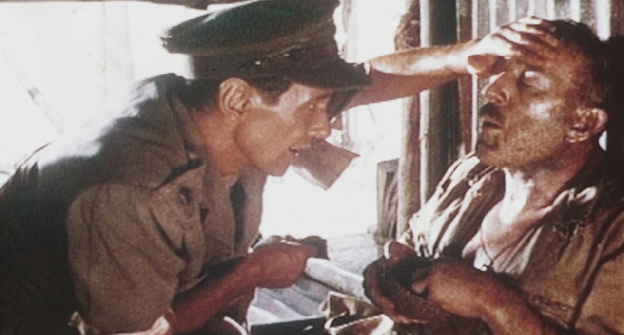 Oberst Nicholson (Alec Guinness, l.) ist am Ende seiner Kräfte angelangt. Major Clipton (James Donald, l.) kümmert sich um den Verletzten ...